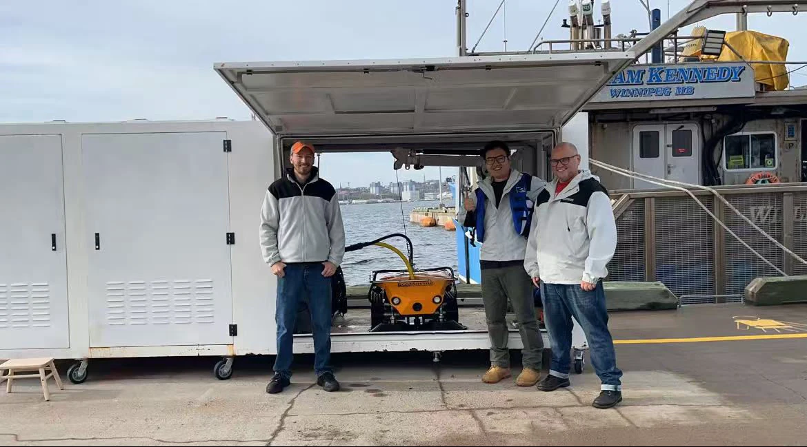 EcoMarine team beside OmniBot and its mobile support equipment at the waterfront